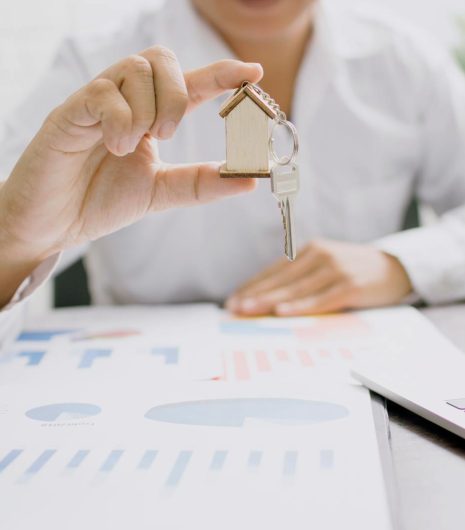 Real estate professional presenting a house model with keys, symbolising property investment and ownership