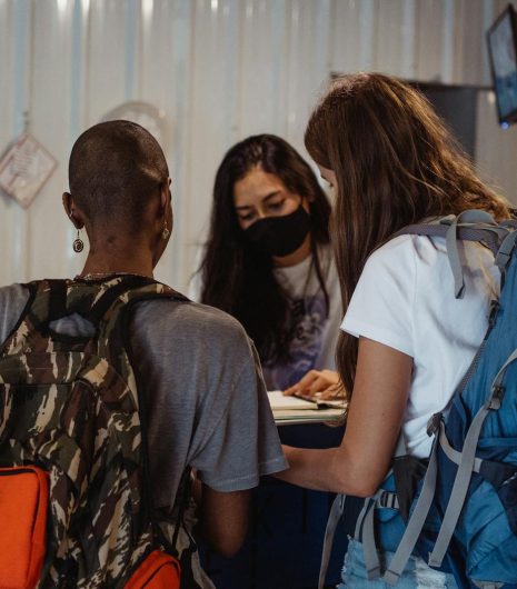 Two travelers with backpacks check in at a hostel reception counter