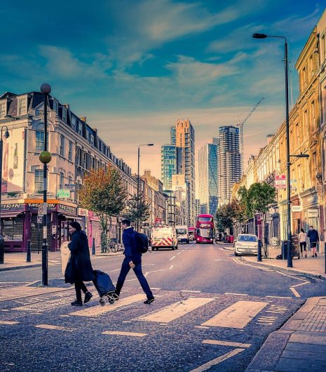 couple of individuals strolling together along a city street, surrounded by urban scenery